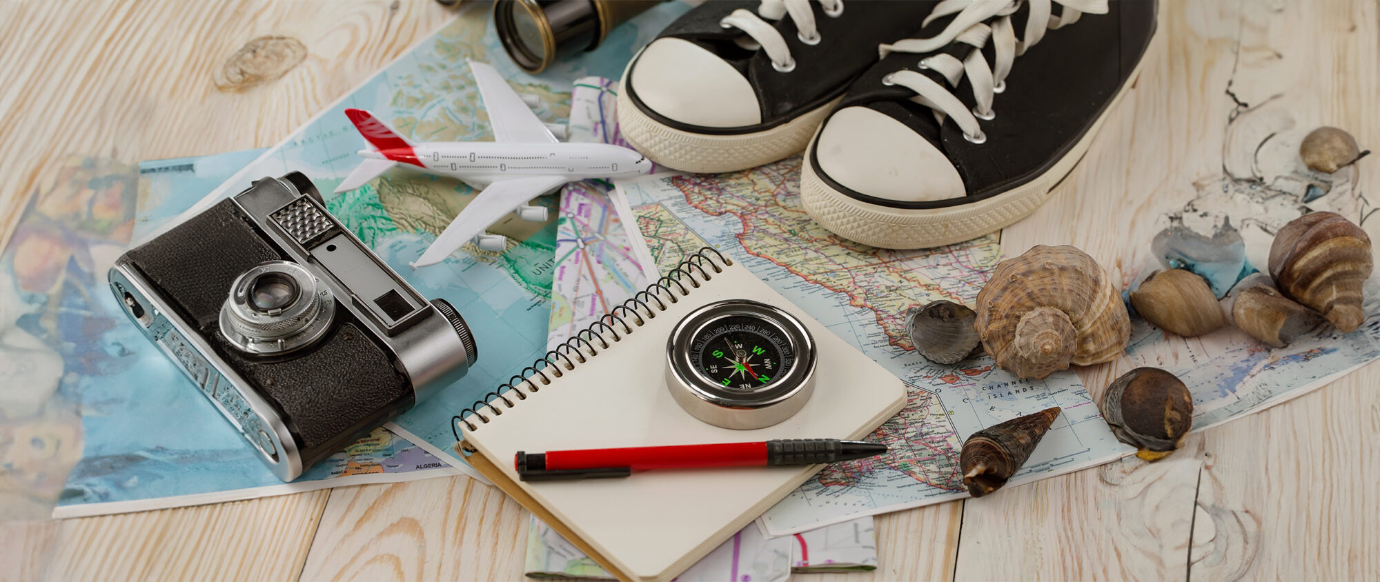 Items symbolizing dental travel planning – maps, compass, camera, airplane model.
