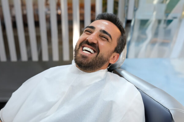 Smiling patient after Hollywood Smile treatment in dental chair